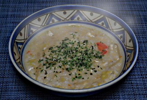 ゆげが立っている、肉団子と野菜の中華風スープの余りを利用した、卵雑炊